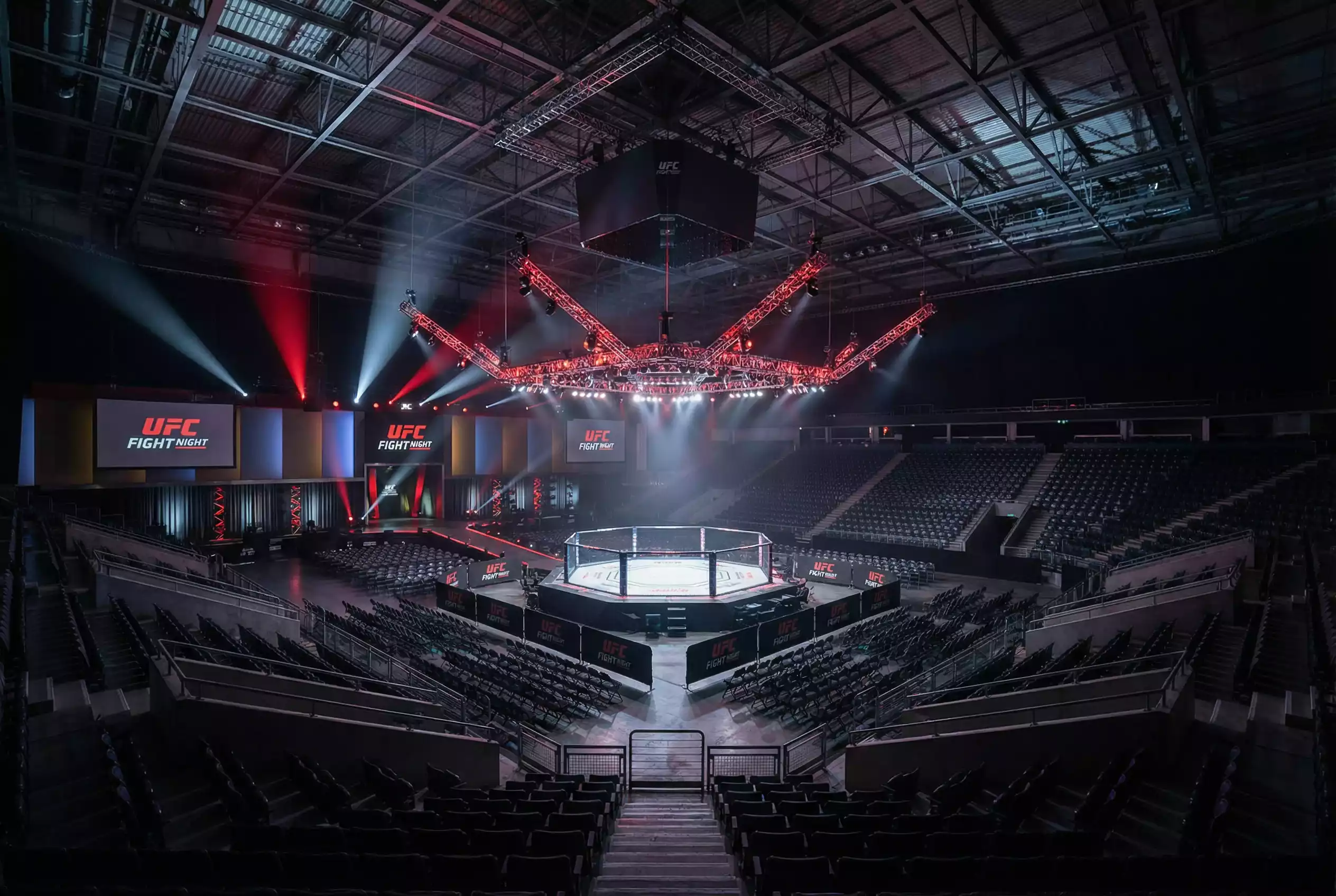 Arena iluminada durante un evento de UFC con el octágono en el centro